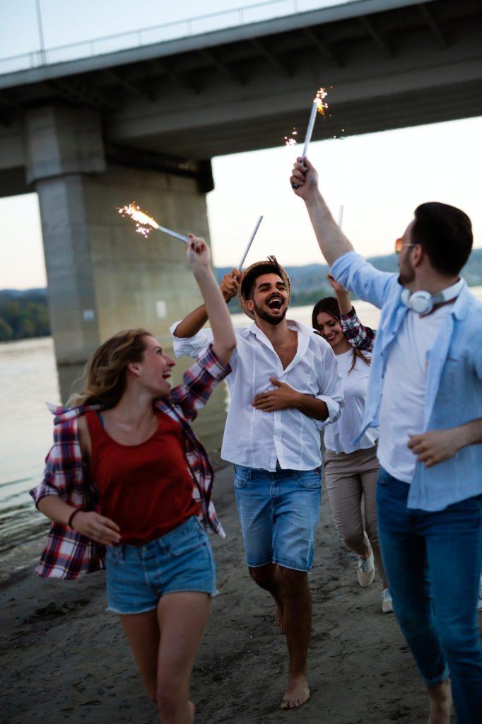 Happy group of friends lighting sparklers and enjoying freedom from addiction after treatment from Saving My Tomorrow